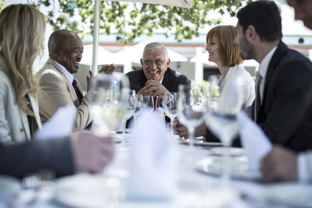 Profesionales conversando durante una comida corporativa en un ambiente relajado y luminoso.