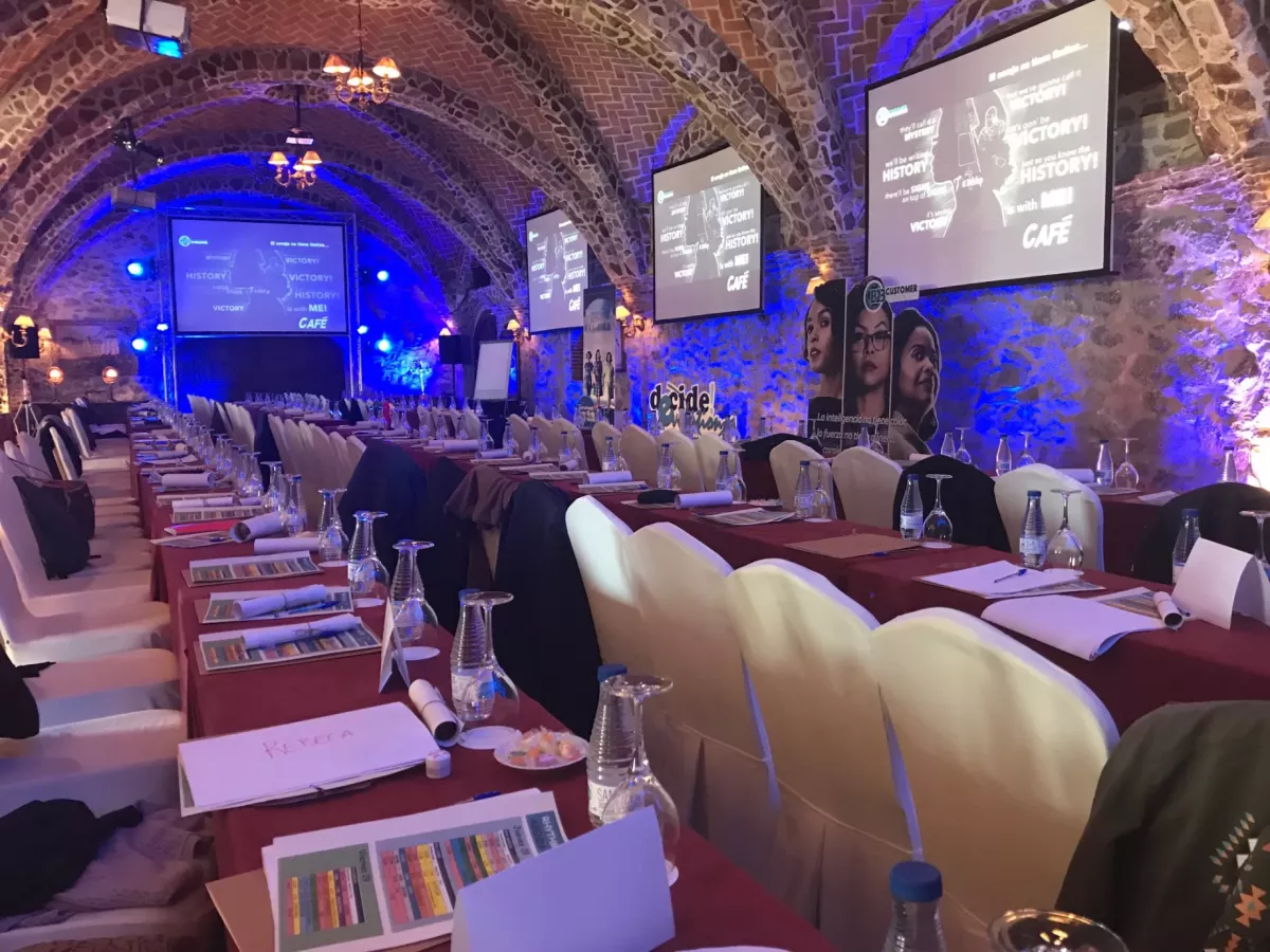 Sala Capellanía de Aldea Santillana preparada para un evento corporativo con techos abovedados de piedra y pantallas